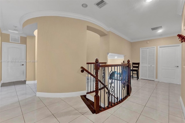 hall with light tile patterned floors, visible vents, and an upstairs landing