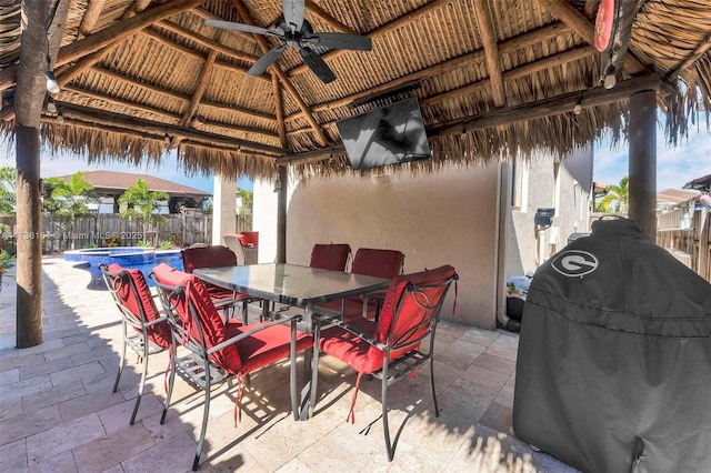 view of patio featuring a ceiling fan, outdoor dining space, fence, and a gazebo