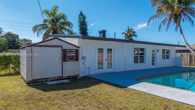 back of property with an outbuilding, a yard, a patio area, and french doors