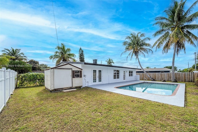 view of pool featuring a patio, a yard, and a storage shed