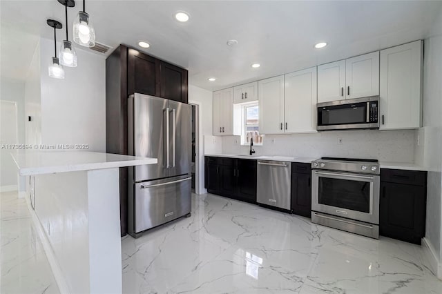 kitchen with sink, white cabinetry, pendant lighting, stainless steel appliances, and decorative backsplash