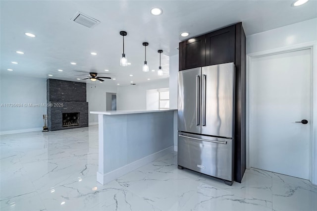 kitchen with pendant lighting, a large fireplace, ceiling fan, kitchen peninsula, and high end fridge