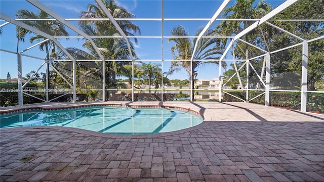 view of pool with a patio, a water view, and glass enclosure