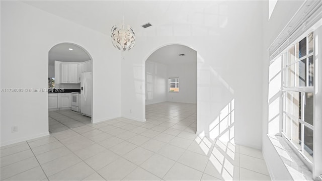 unfurnished room with a chandelier, a high ceiling, and light tile patterned floors