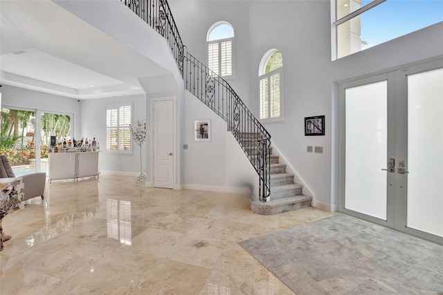 entryway with french doors, a raised ceiling, and a high ceiling