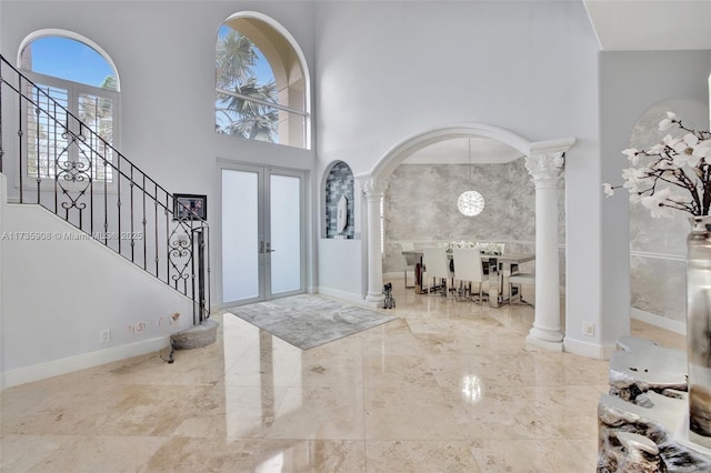 entryway featuring ornate columns, a high ceiling, and french doors