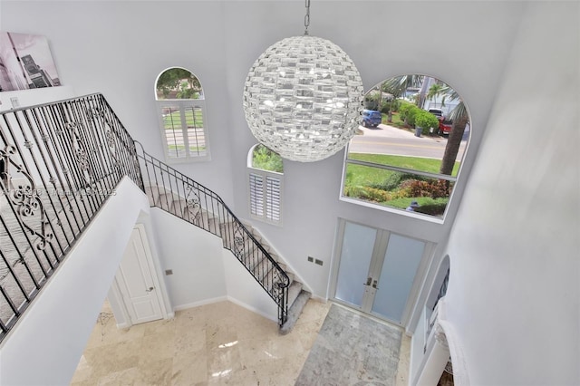 stairs featuring a notable chandelier and a towering ceiling