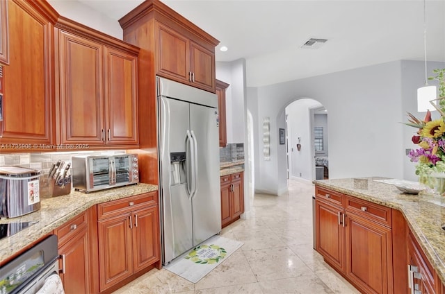 kitchen featuring light stone counters, appliances with stainless steel finishes, light tile patterned flooring, and decorative backsplash