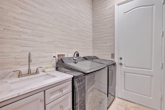 laundry room with cabinets, washer and clothes dryer, sink, and tile walls