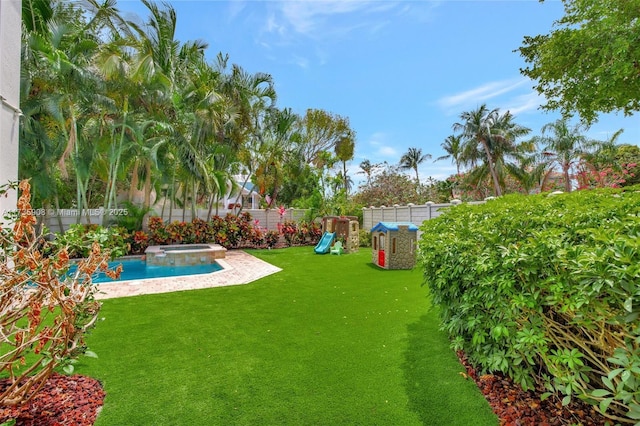 view of yard featuring a playground and an in ground hot tub