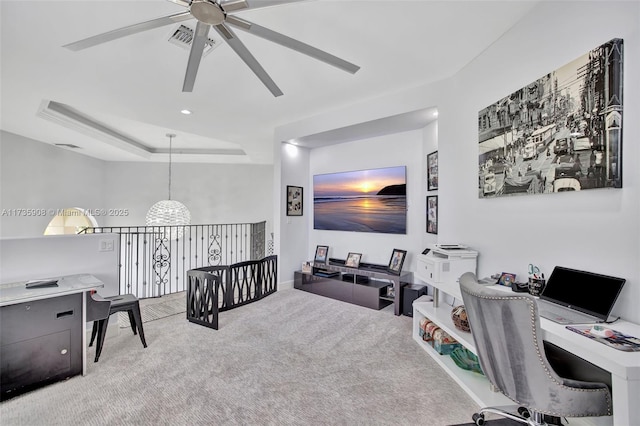 carpeted office space with ceiling fan and a raised ceiling