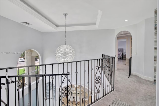 hallway featuring light colored carpet, a notable chandelier, and a tray ceiling