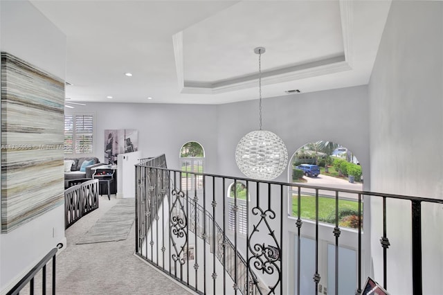 corridor featuring a notable chandelier, a tray ceiling, and carpet