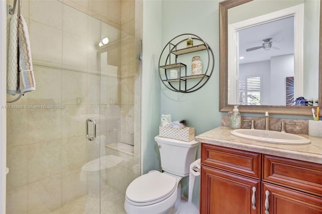 bathroom featuring ceiling fan, vanity, toilet, and a shower with shower door