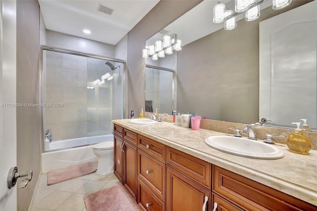 full bathroom with tile patterned flooring, bath / shower combo with glass door, vanity, and toilet