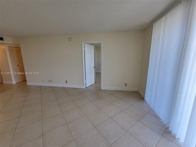 empty room featuring a textured ceiling and light tile patterned floors