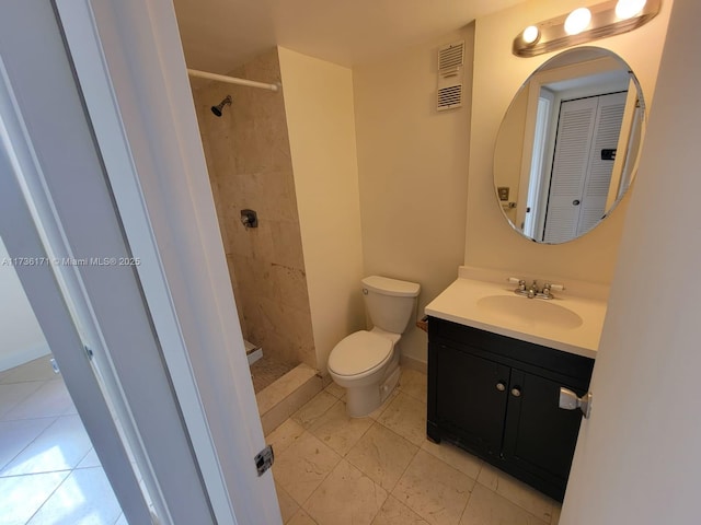 bathroom featuring vanity, a tile shower, and toilet