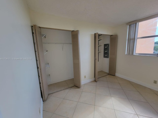 unfurnished bedroom with light tile patterned floors, a closet, and a textured ceiling