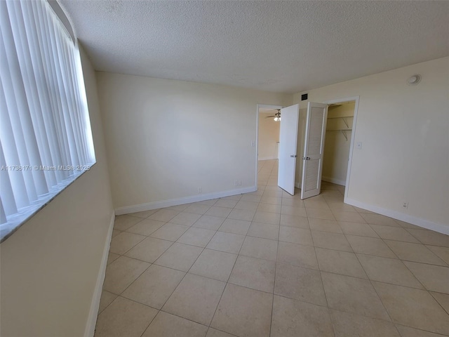 tiled empty room featuring ceiling fan and a textured ceiling