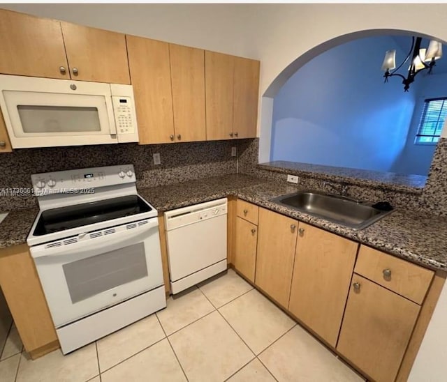 kitchen featuring pendant lighting, sink, backsplash, dark stone counters, and white appliances