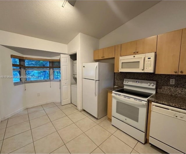 kitchen with tasteful backsplash, light tile patterned floors, white appliances, and dark stone counters