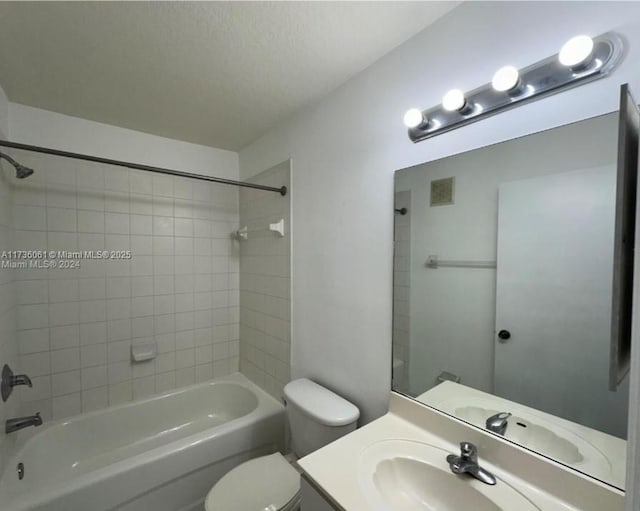 full bathroom with tiled shower / bath, vanity, and toilet