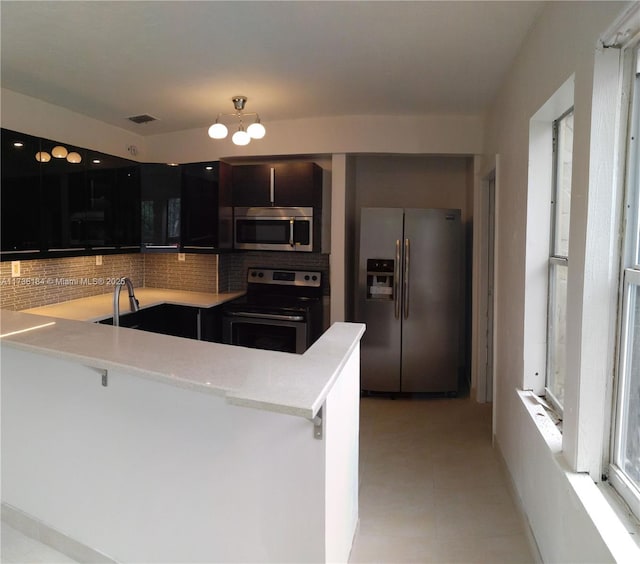 kitchen featuring a kitchen breakfast bar, stainless steel appliances, kitchen peninsula, and decorative backsplash