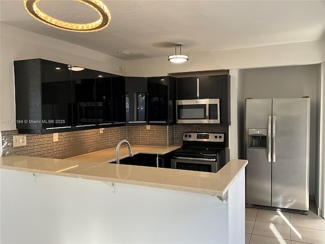 kitchen featuring tasteful backsplash, light tile patterned floors, a kitchen breakfast bar, kitchen peninsula, and stainless steel appliances