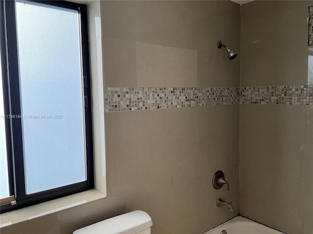 bathroom featuring tiled shower / bath and toilet