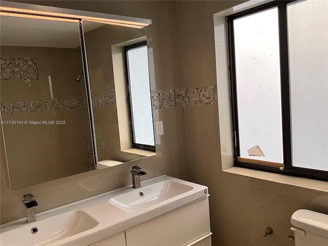 bathroom featuring vanity, toilet, and tile walls