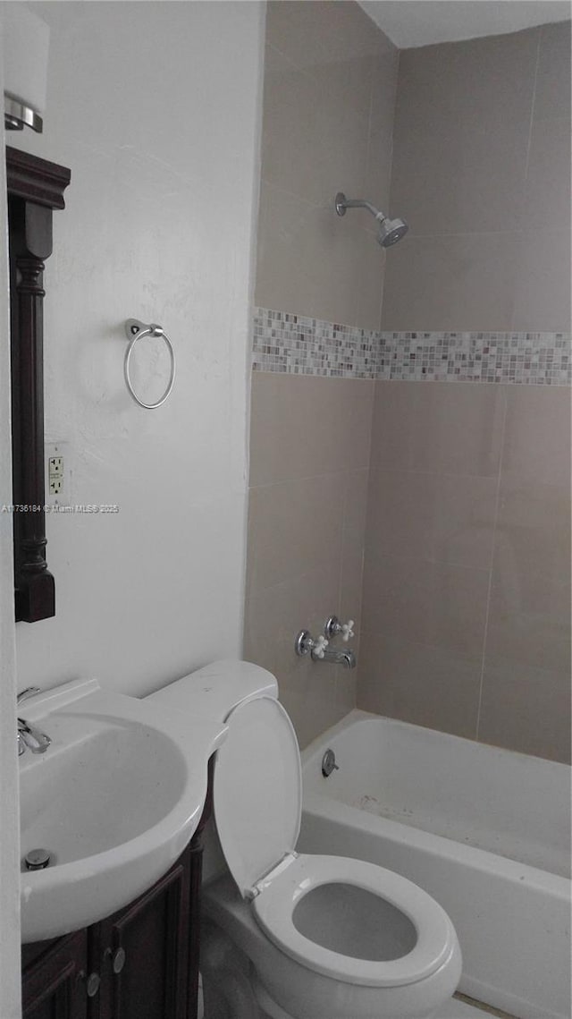 full bathroom featuring vanity, tiled shower / bath, and toilet