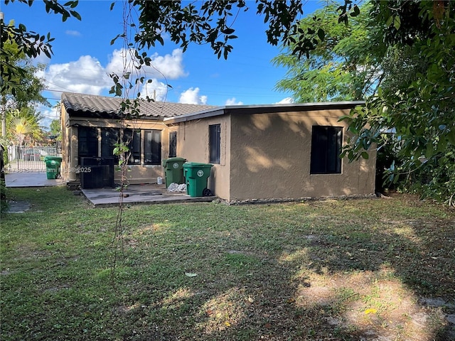 rear view of property featuring a sunroom, a lawn, and a patio area