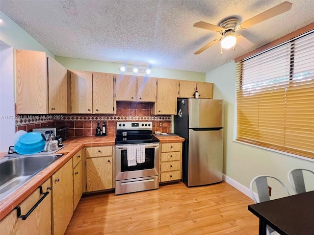 kitchen featuring appliances with stainless steel finishes, light brown cabinetry, tasteful backsplash, ceiling fan, and light wood-type flooring