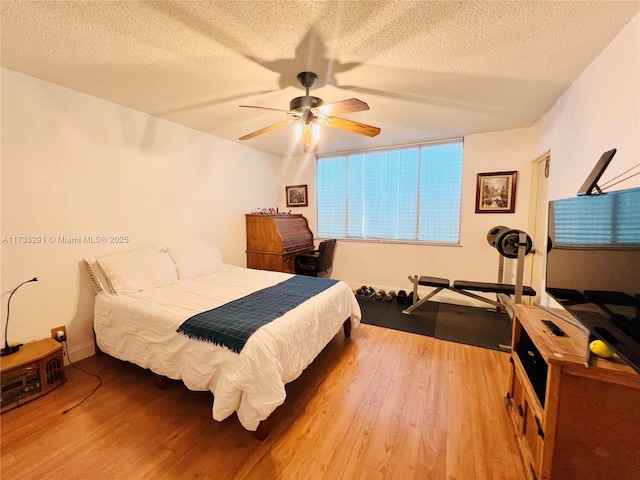 bedroom with hardwood / wood-style flooring, ceiling fan, and a textured ceiling