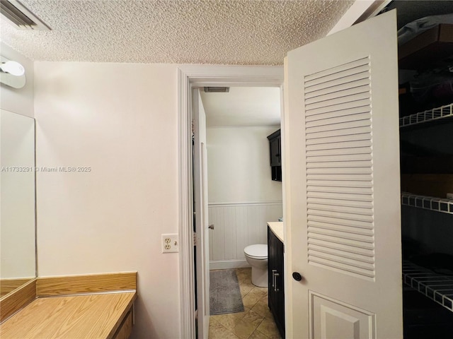 bathroom featuring vanity, toilet, and a textured ceiling