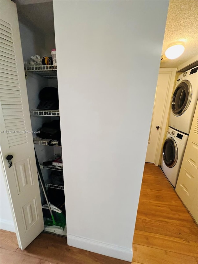 clothes washing area featuring stacked washing maching and dryer and light hardwood / wood-style floors