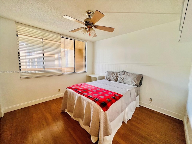 bedroom with ceiling fan, dark hardwood / wood-style floors, and a textured ceiling