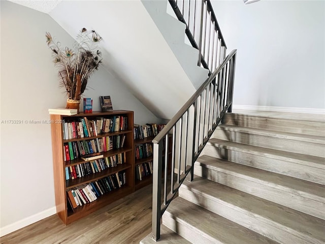 staircase featuring lofted ceiling and hardwood / wood-style flooring