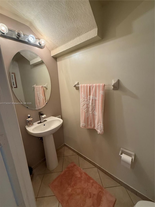 bathroom featuring tile patterned flooring, sink, vaulted ceiling, and a textured ceiling