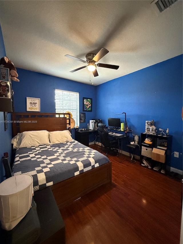 bedroom featuring dark wood-type flooring, ceiling fan, and a textured ceiling