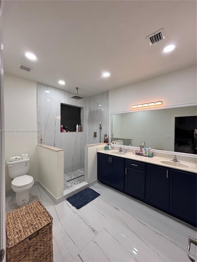 bathroom with vanity, toilet, and tiled shower