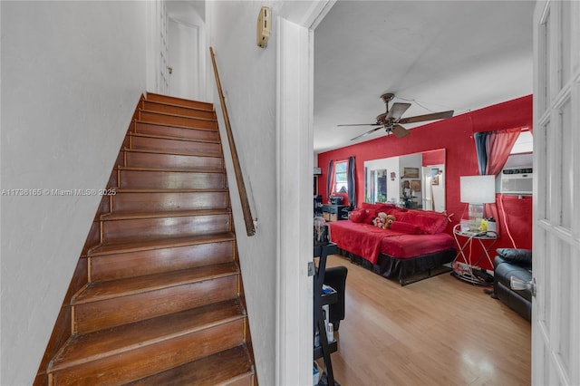 stairway with hardwood / wood-style flooring, cooling unit, and ceiling fan