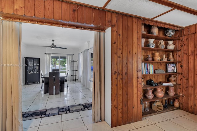 dining space featuring ceiling fan, light tile patterned floors, built in features, and wooden walls