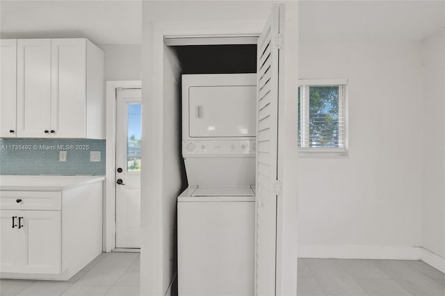 washroom with plenty of natural light, stacked washer / drying machine, and light tile patterned floors