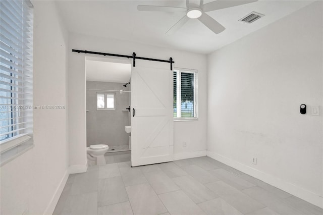 interior space featuring a tile shower, ceiling fan, and toilet