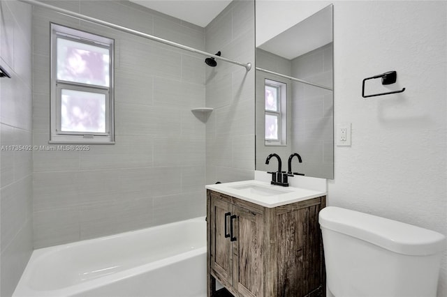 full bathroom featuring vanity, tiled shower / bath, a wealth of natural light, and toilet