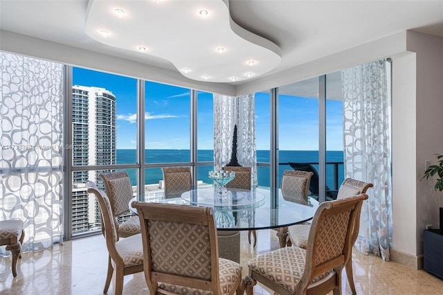 dining space with a water view, a wall of windows, and a healthy amount of sunlight