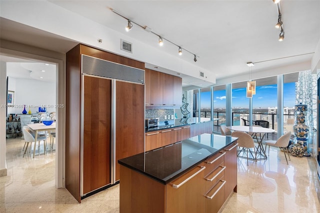 kitchen featuring track lighting, paneled built in fridge, a kitchen island, pendant lighting, and backsplash