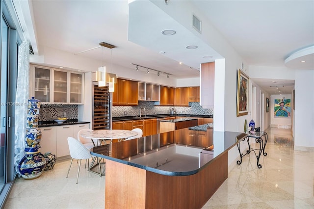 kitchen featuring tasteful backsplash, sink, kitchen peninsula, and decorative light fixtures