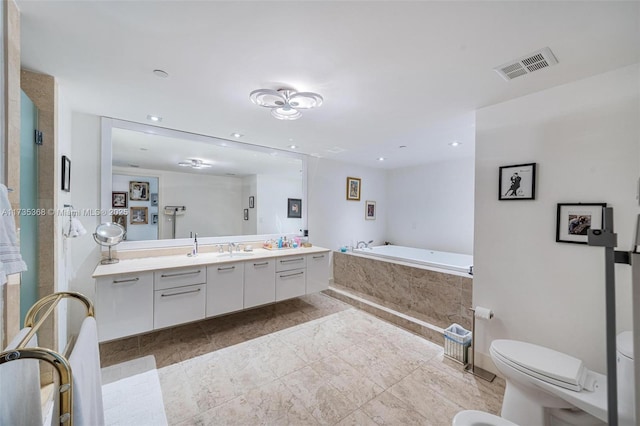 bathroom featuring vanity, tiled bath, and toilet